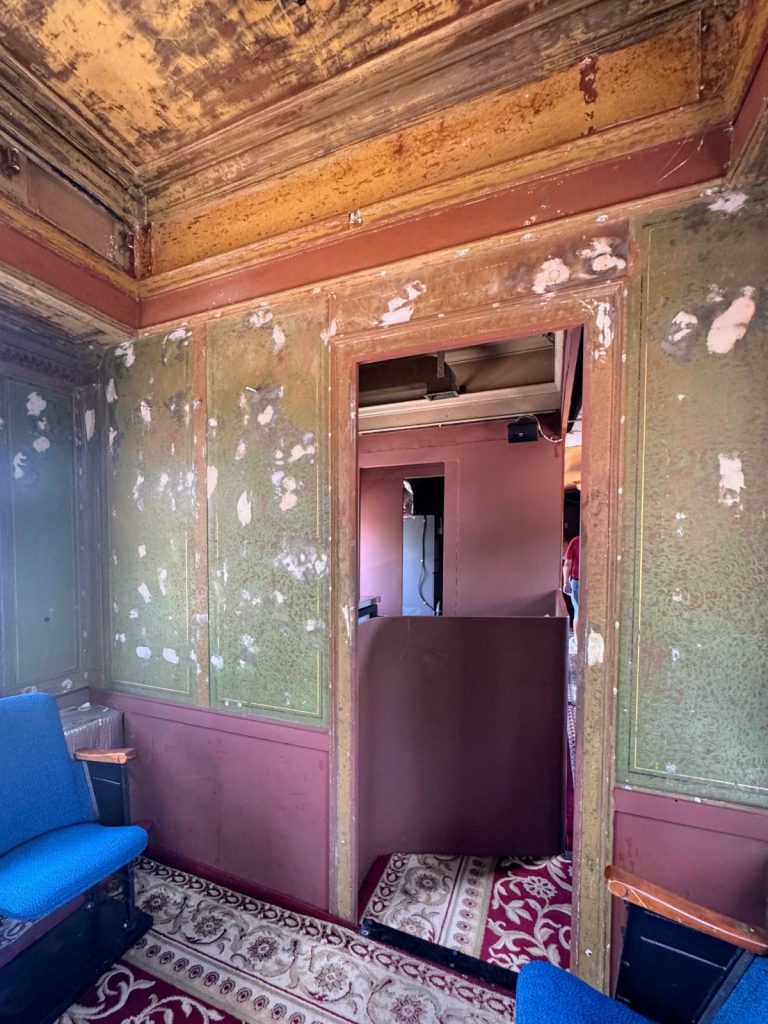 1900's train car wall in the midst of being restored. Green walls with patching and magenta paint on lower part.