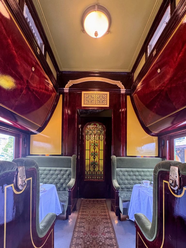 Interior of dining car with green seats, white table cloths and gleaming wood restored by the Colebrookdale Railroad group.