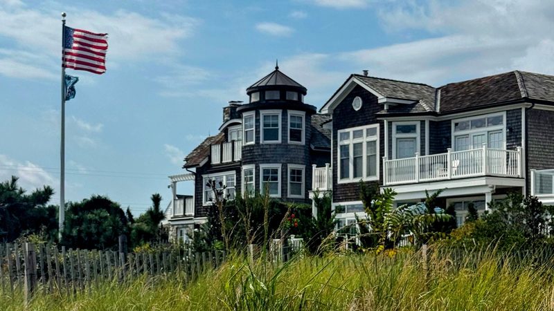 House on Rehoboth Beach with beach grasses in foreground and flag flying.