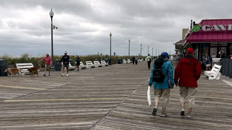 People walking on the Rehoboth Beach Boardwalk under cloudy skies.